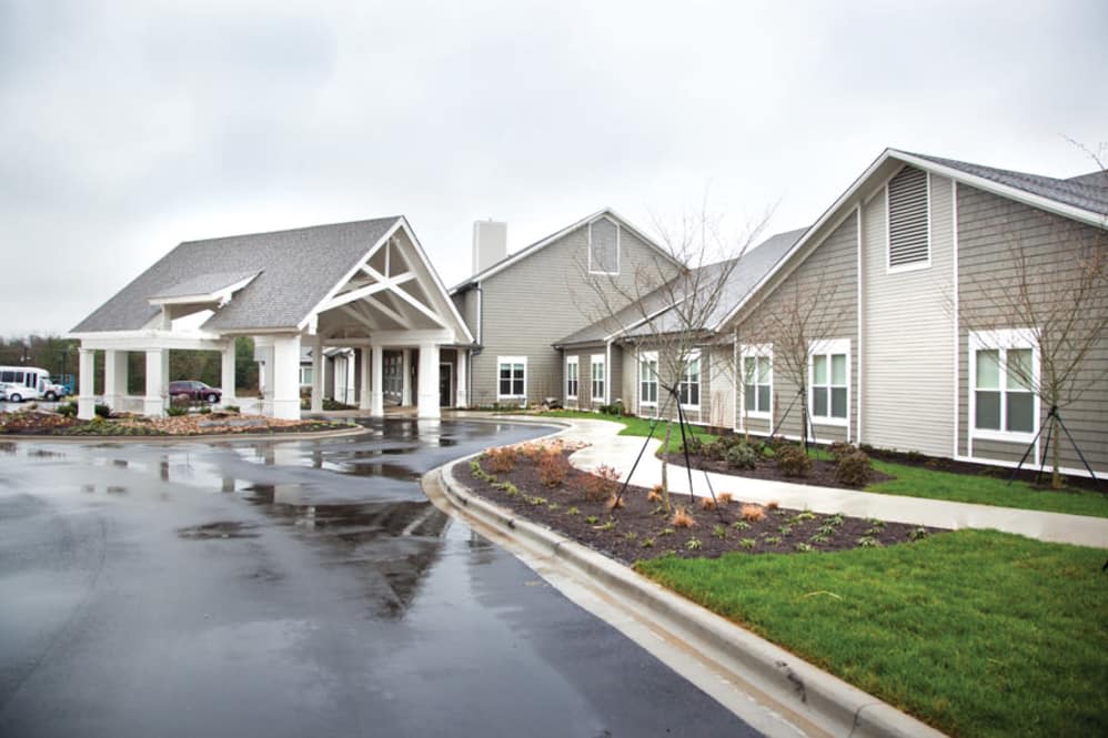 A modern building exterior with an overcast sky and well-maintained landscaping.
