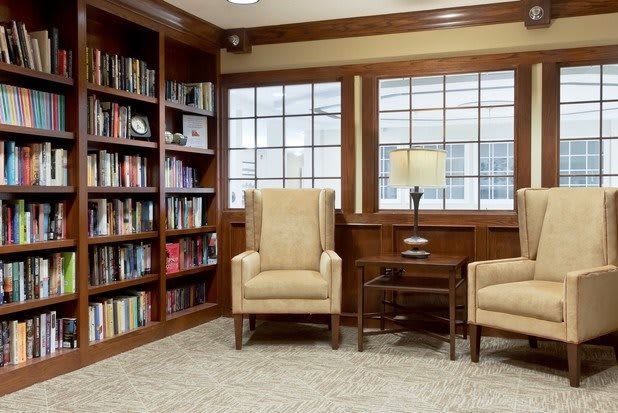 Cozy reading corner with armchairs and a bookshelf in a library setting.
