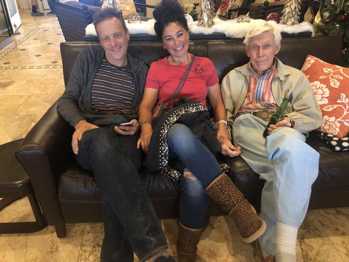 Three people sitting on a couch in a casual setting.