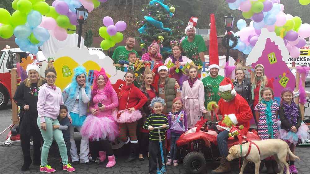 A festive group gathering with people in colorful costumes, surrounded by balloons and holiday decorations.