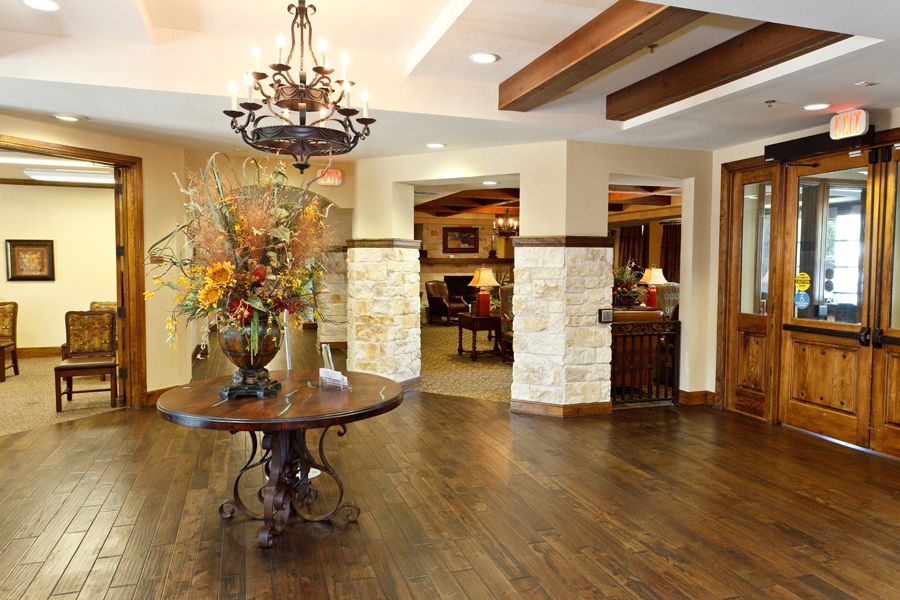 A beautifully designed lobby with elegant furniture and a chandelier, featuring wood flooring and decorative flowers.
