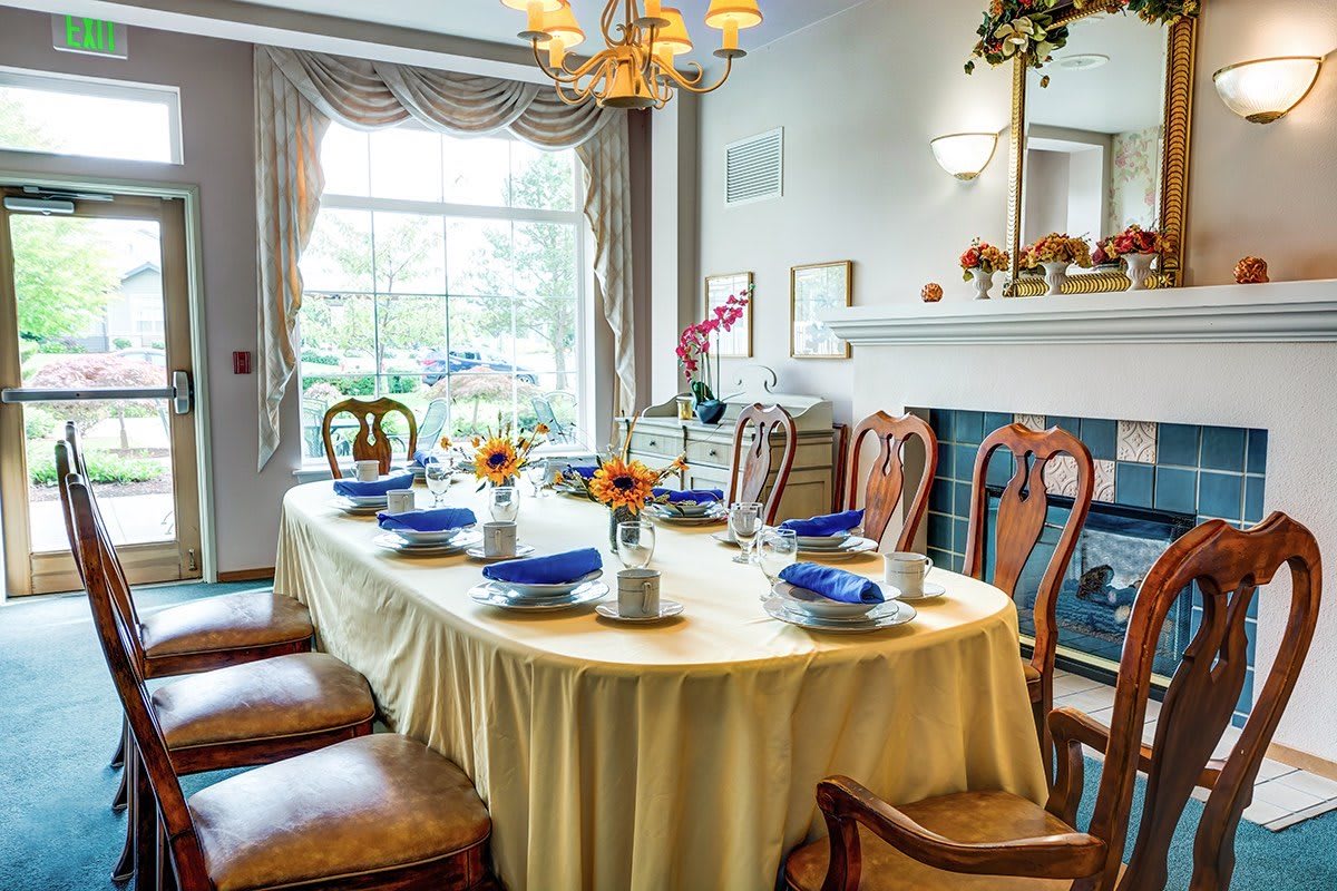 A beautifully set dining table in a well-lit room with elegant decor and sunflowers as a centerpiece.