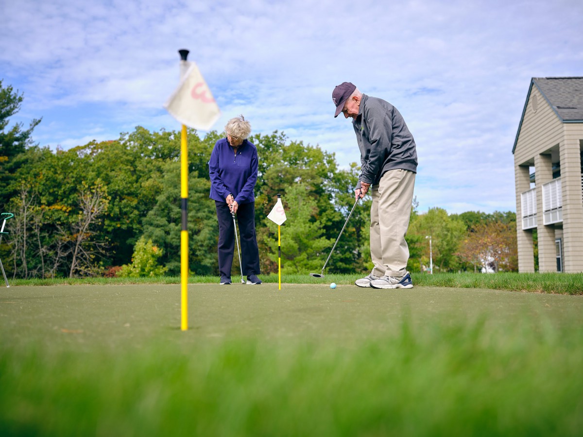 Two senior individuals enjoying a game of golf outdoors on a sunny day.