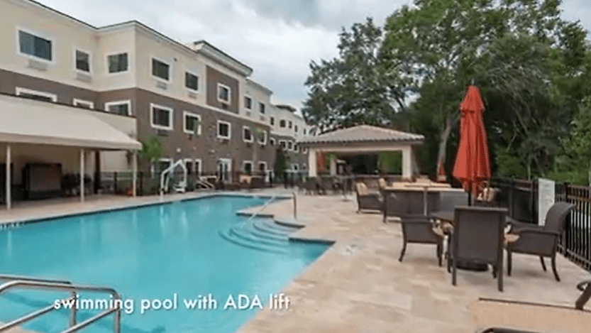 Outdoor swimming pool with ADA lift and seating area.