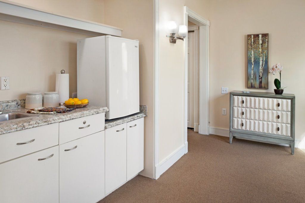 A well-organized kitchen area with modern appliances and cabinets, featuring a bowl of fruit on the countertop.