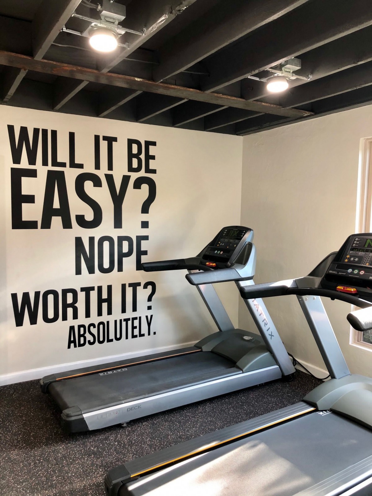 Home gym with motivational wall art and treadmills.