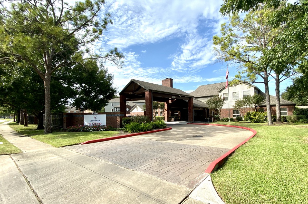 A residential building with a covered entrance and a surrounding driveway on a sunny day.