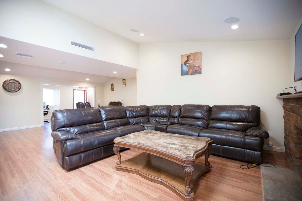 A spacious living room with a large sectional sofa and a wooden coffee table on hardwood floors.