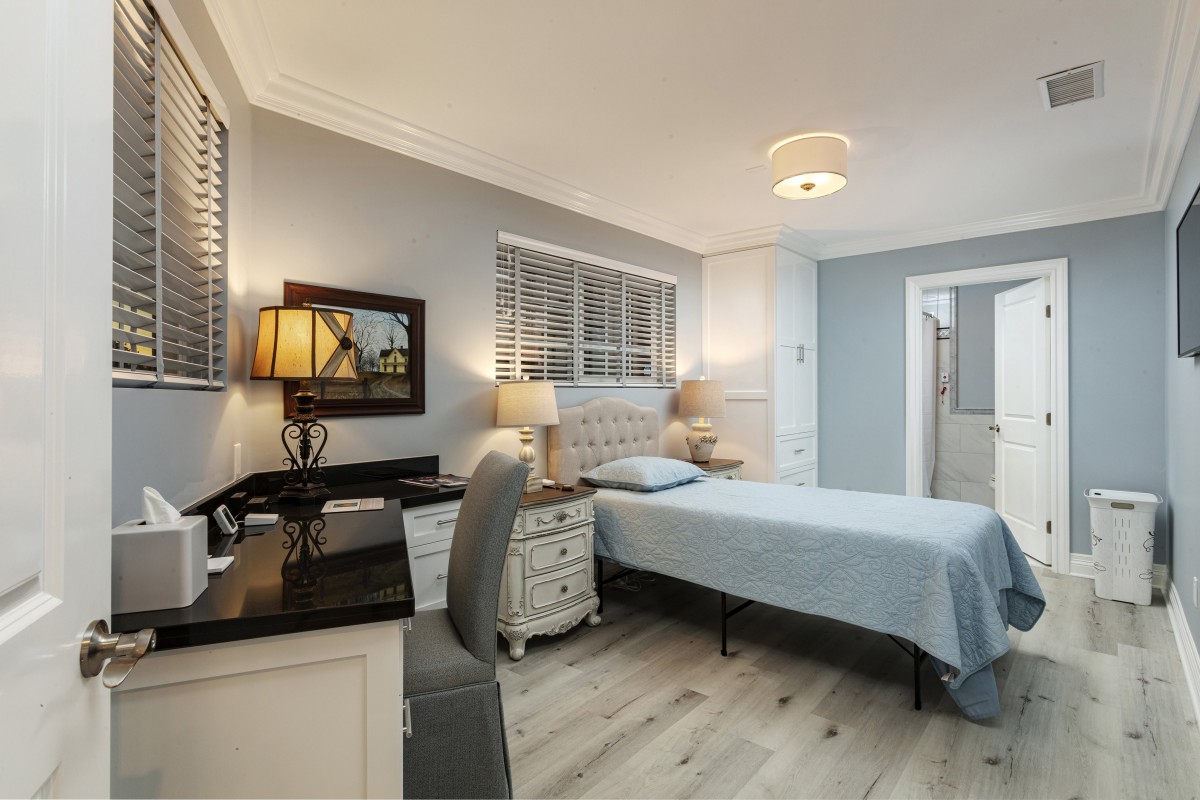 A modern bedroom featuring a single bed, desk, and stylish lighting against a backdrop of blue walls.