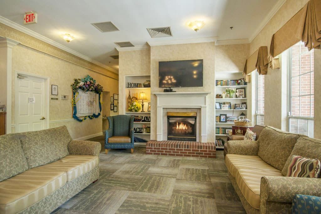 A cozy living room with a fireplace, surrounded by sofas and bookshelves.