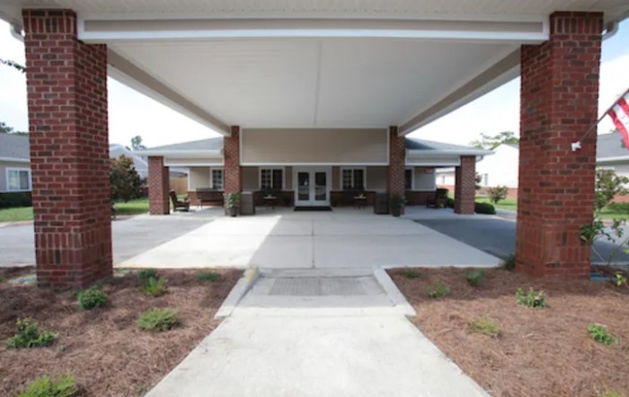 A covered entrance to a building with a wide driveway.