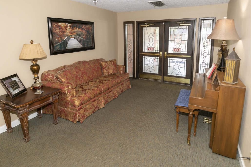 A cozy living room with a patterned sofa, wooden table, and a painting on the wall.