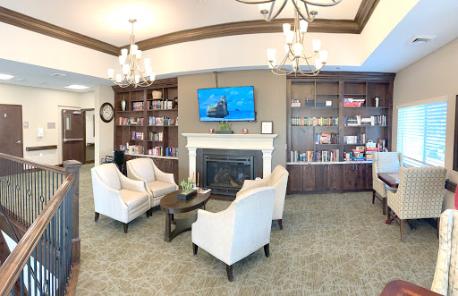 A cozy and inviting living room area featuring comfortable chairs, a fireplace, and shelves filled with books.