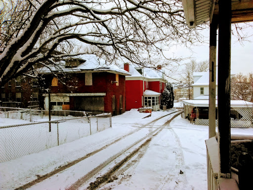 A tranquil winter scene featuring snow-covered houses and bare tree branches.