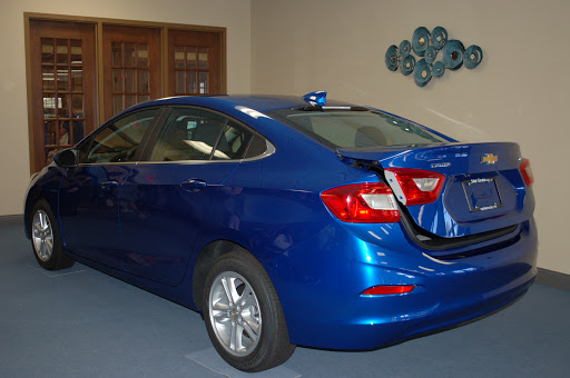 A blue sedan parked indoors with its trunk open.