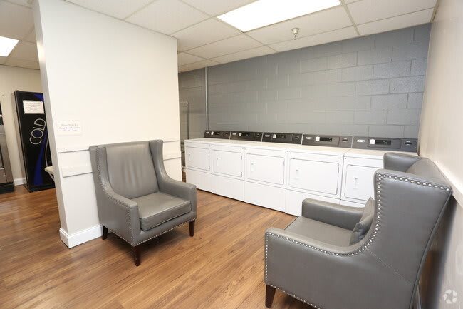 A laundry room with comfortable seating and a row of washing machines.