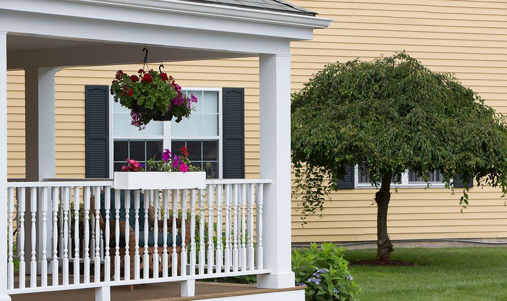 A cozy porch with hanging flowers and a well-maintained garden in front of a house.