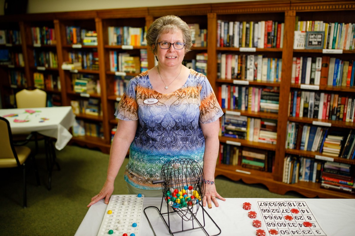 A person stands in front of bingo equipment in a library setting.