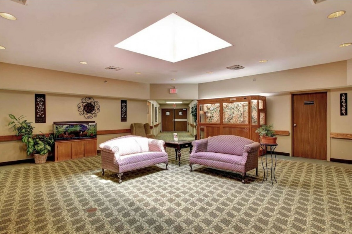 A cozy lobby area featuring two sofas, a patterned carpet, and a skylight.