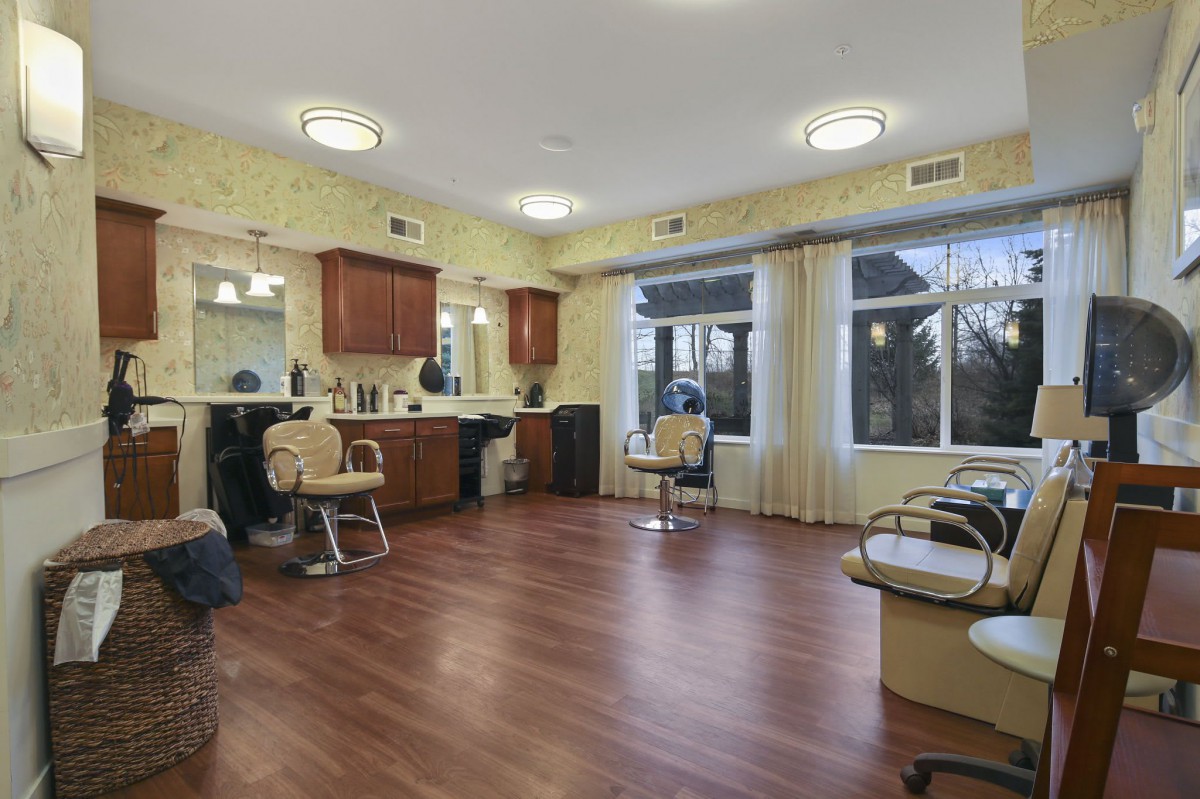 An empty beauty salon with styling chairs and mirrors along the walls.