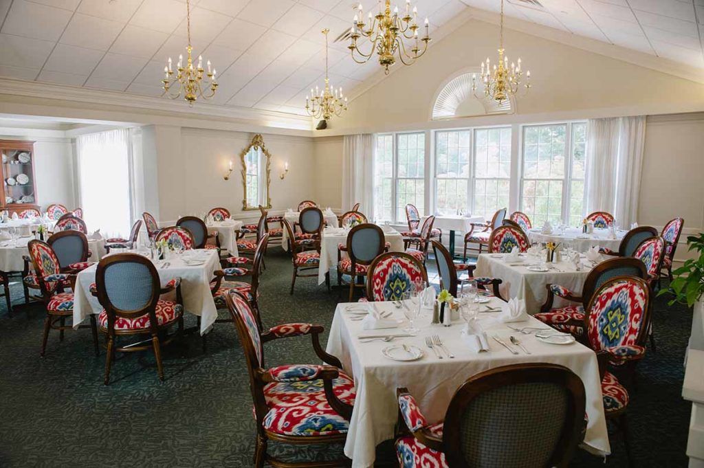 An elegantly designed restaurant dining room with set tables and chandeliers.