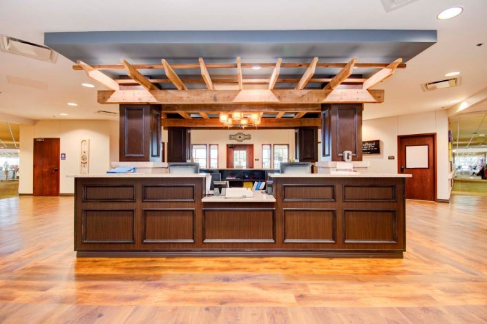 A modern office reception area featuring a wooden desk and contemporary lighting.