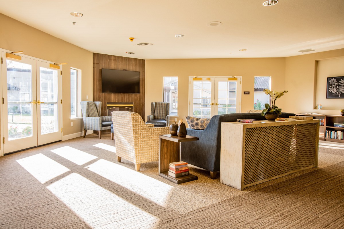 A sunlit living room with comfortable seating and a large television.