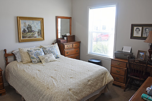 A cozy bedroom featuring a comfortable bed, wooden furniture, and bright natural light streaming through the window.