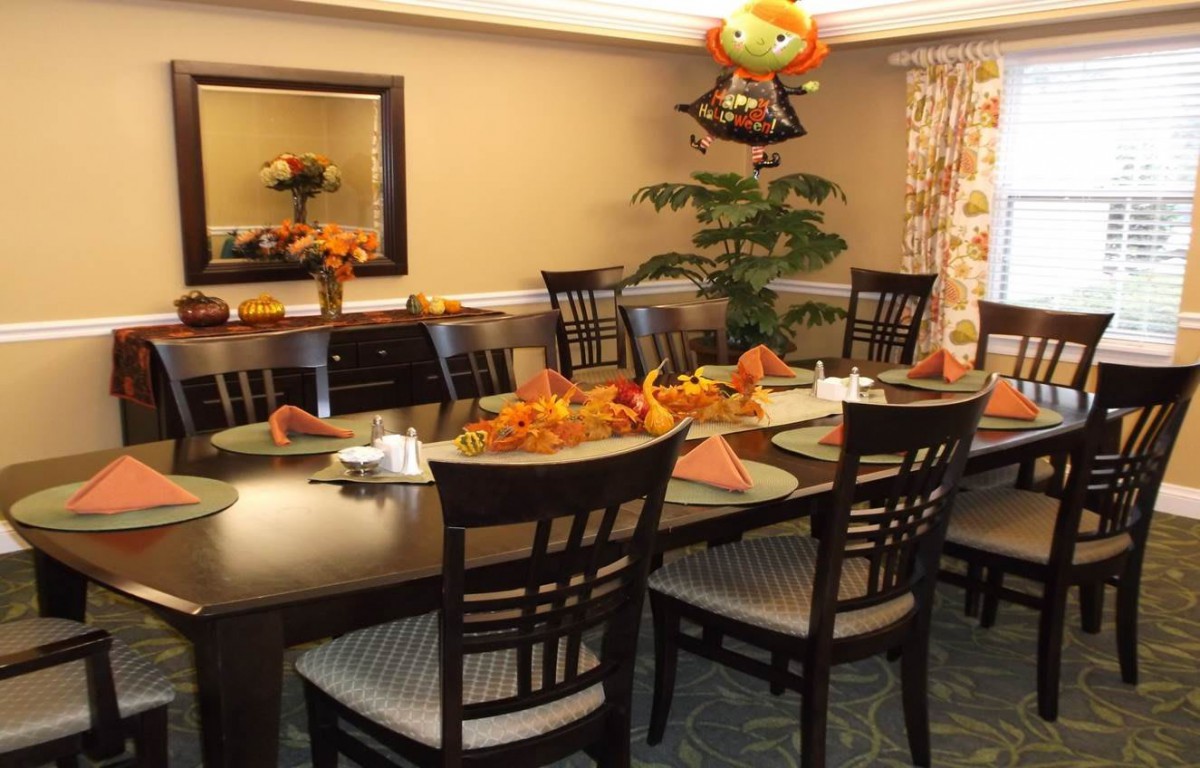 A dining room decorated for an autumn holiday, featuring a table set with festive decorations.