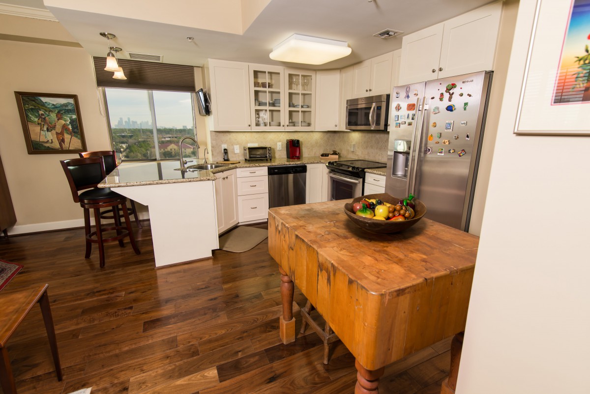 A modern kitchen with stainless steel appliances and wooden flooring.