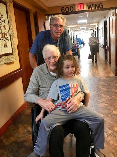 A heartwarming moment shared between three generations in a hospital hallway.