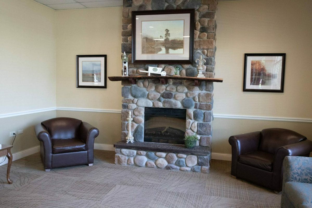 A cozy lounge area featuring a stone fireplace with artwork above and leather chairs on either side.