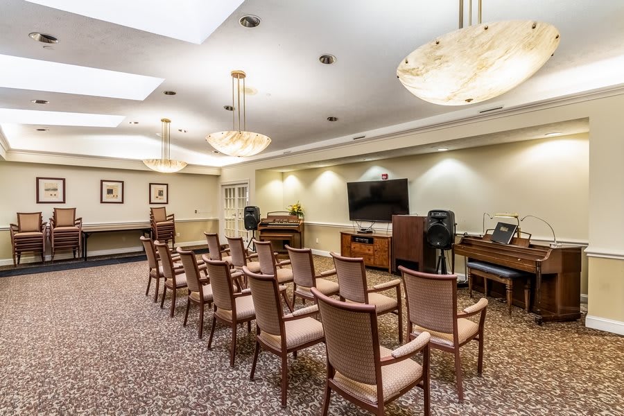 A well-lit conference room with several chairs arranged in rows facing a television.