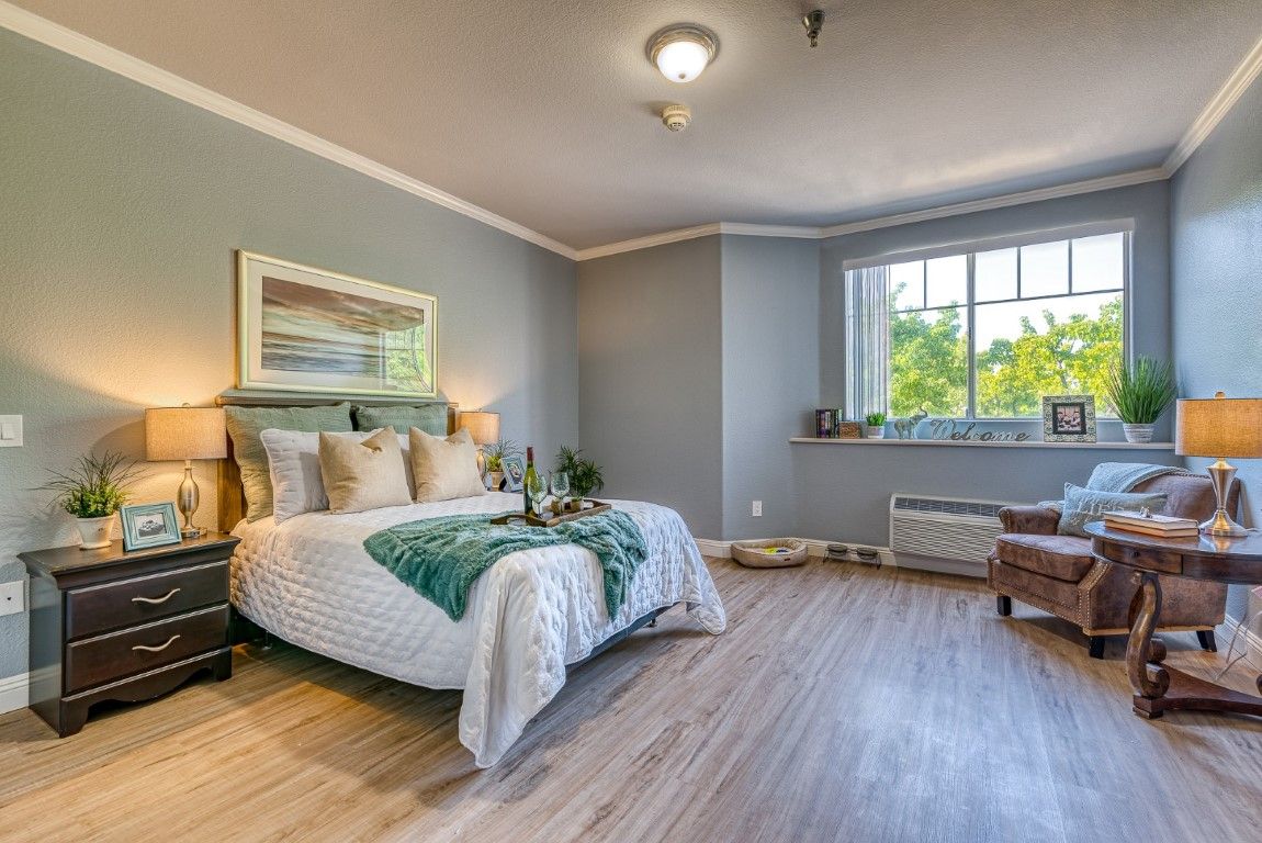 A modern and cozy bedroom with a large window, featuring wood flooring and stylish decor.