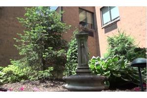 A statue bust in a garden surrounded by greenery.