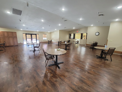A spacious dining area featuring multiple tables and chairs, illuminated by bright lights.