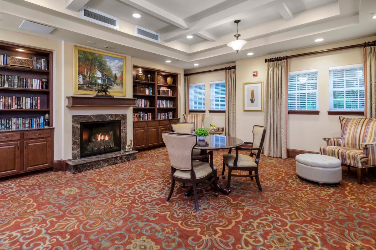A cozy living room featuring a fireplace, bookshelves, and a seating area with a table and chairs.