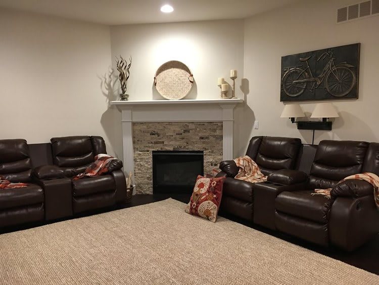 A cozy living room featuring a fireplace, two leather sofas, and decorative elements.