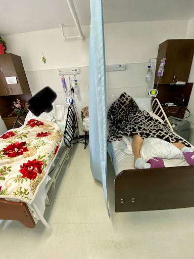 Two hospital beds with patients, separated by a privacy curtain.