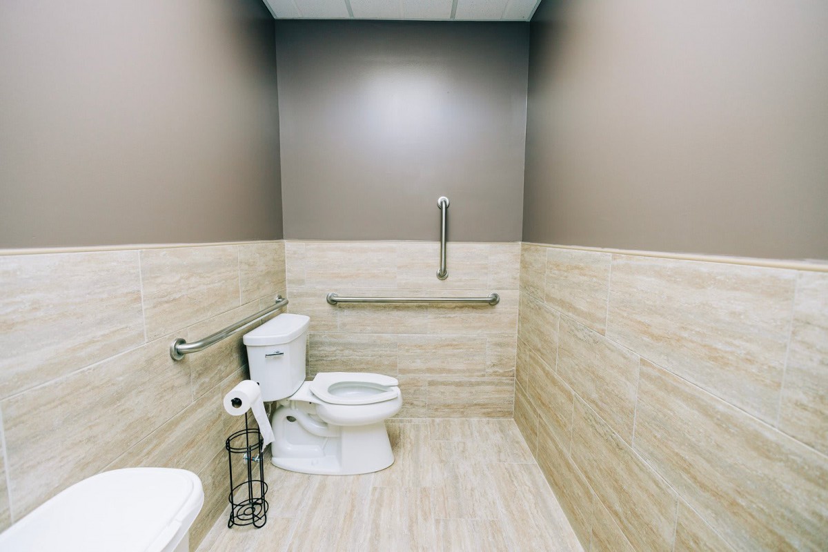An accessible bathroom featuring a toilet with grab bars for support.