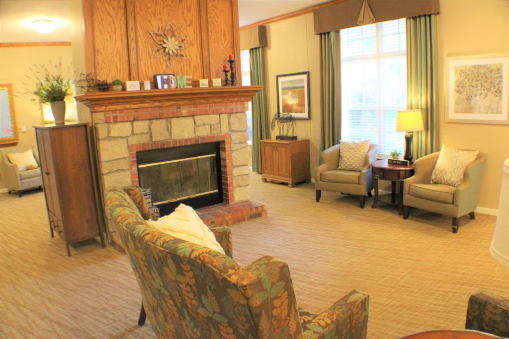 A cozy living room featuring a stone fireplace, armchairs, and warm decor.