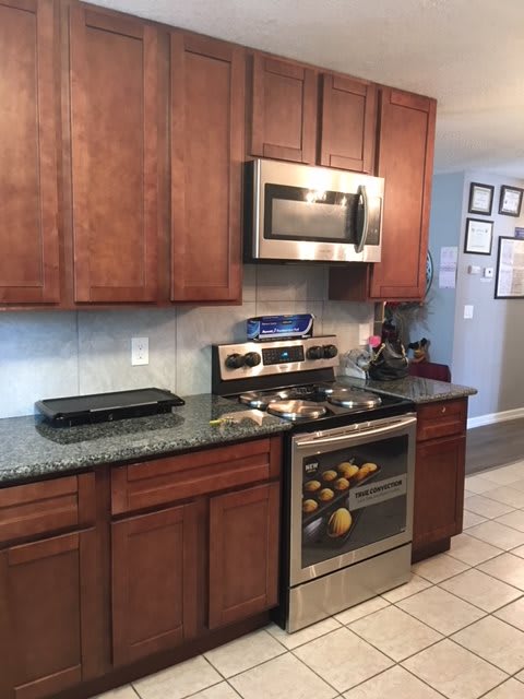 A modern kitchen with wooden cabinets, a microwave, and a stainless steel stove and oven.