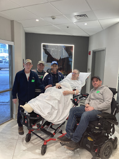 A group of caregivers posing for a photo with a patient in a hospital setting.
