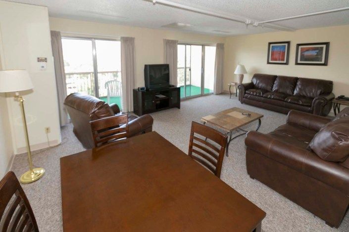 A spacious living room with sofas, a television, and large windows.