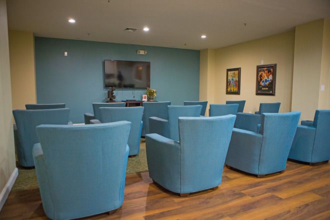 A cozy room with blue theater-style seating, a large TV, and decorative posters on the walls.