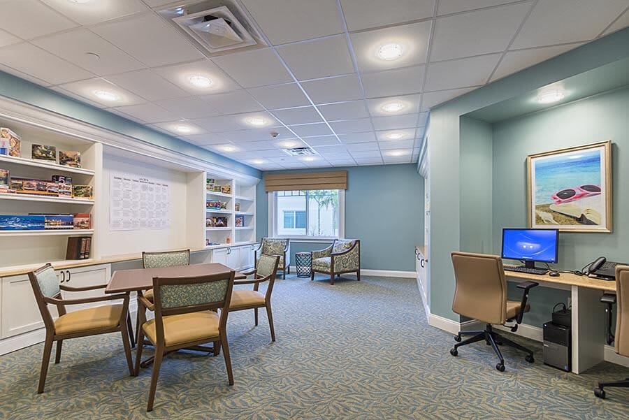 A modern office meeting room with tables, chairs, and a computer station.