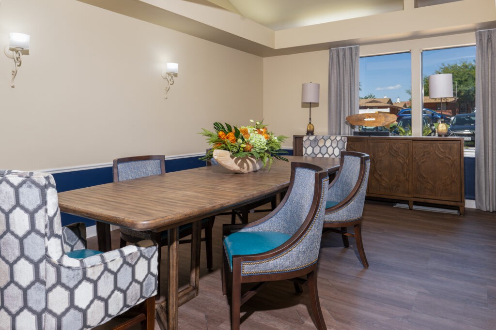 A modern dining room with an elegant table, cushioned chairs, and a floral centerpiece.