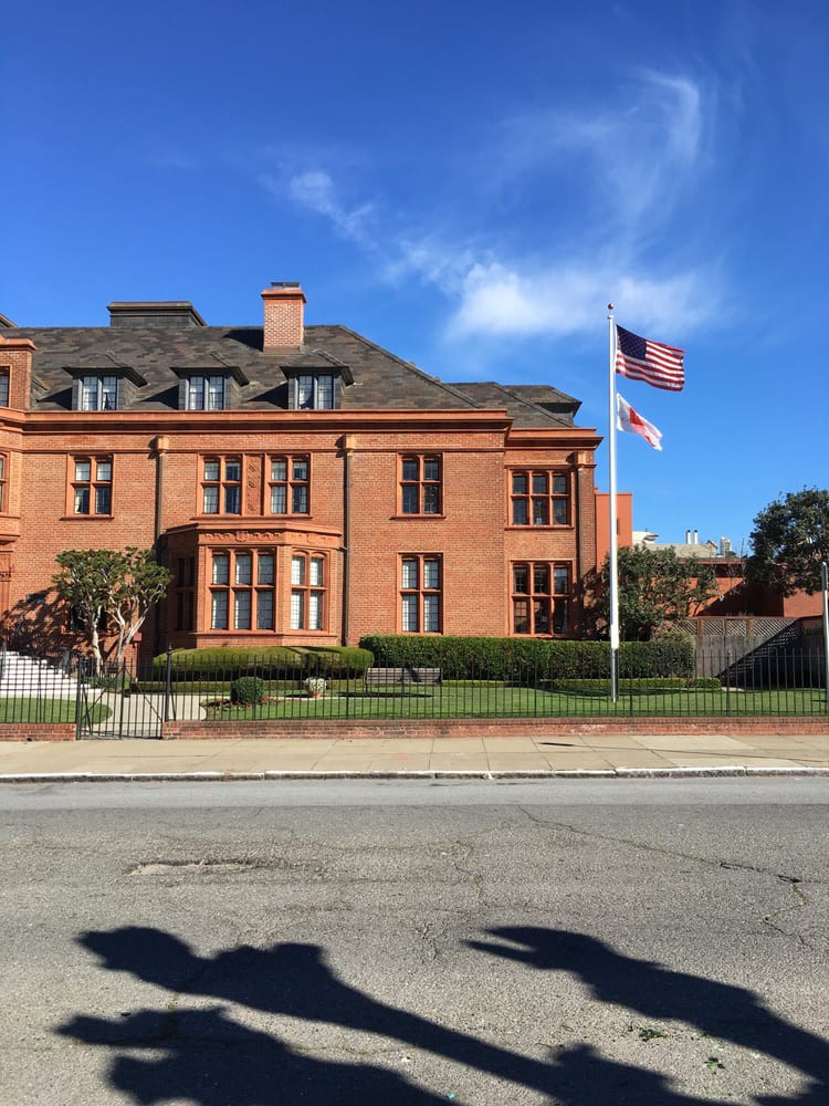 A large brick building with American flags flying in front, set against a clear blue sky.