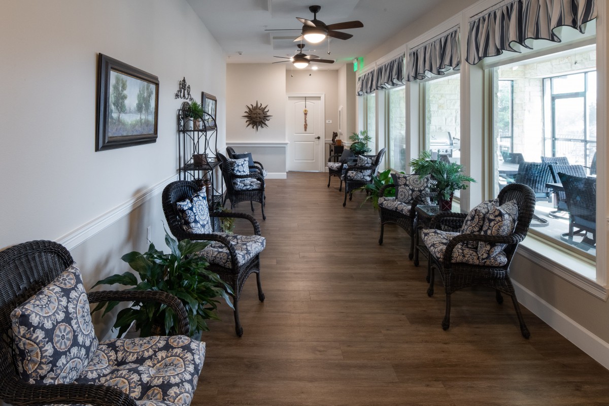 A well-decorated waiting room with rows of chairs and potted plants against large windows.