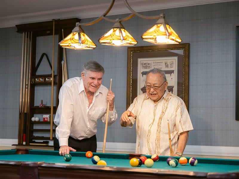 Two men playing billiards and enjoying a game indoors.